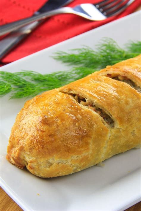 Prepared chicken puff pastry served on a white plate with fresh dill and a red napkin with fork ...