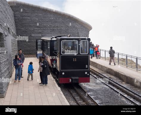 Tourists on platform by Snowdon Mountain Railway train at Hafod Eryri summit station on Mount ...