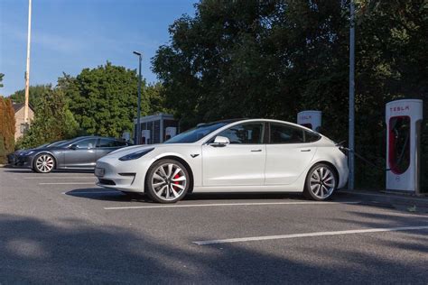 Electric car Tesla Model 3 parks in the shade, in front of Supercharger stations - Creative ...