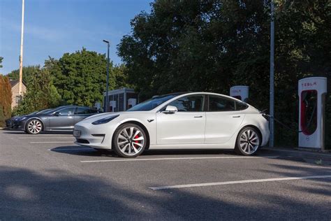 Electric car Tesla Model 3 parks in the shade, in front of Supercharger stations - Creative ...