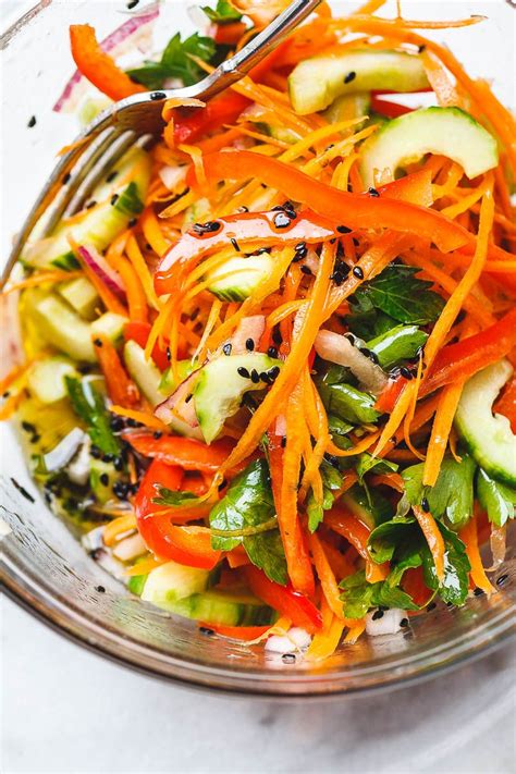 a salad with carrots, cucumbers and other vegetables in a glass bowl