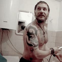 a man with tattoos on his arm holding a hair dryer and comb in the bathroom