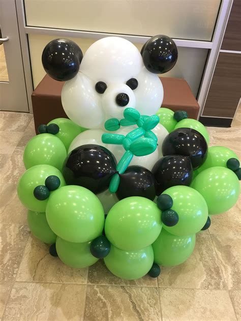 a panda bear balloon sculpture sitting on top of a table next to green and black balloons