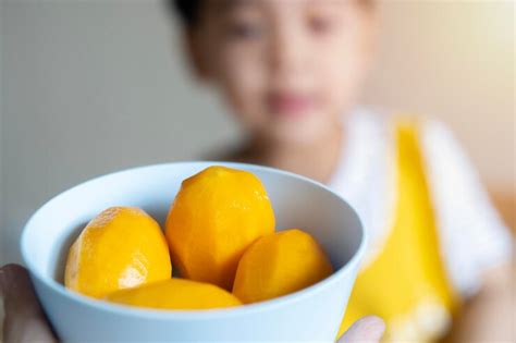 Premium Photo | Happy asian cute child eating yellow fruits and ...