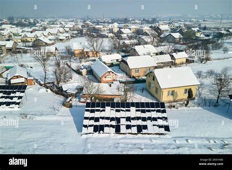 Aerial view of snow melting from covered solar photovoltaic panels installed on house rooftop ...