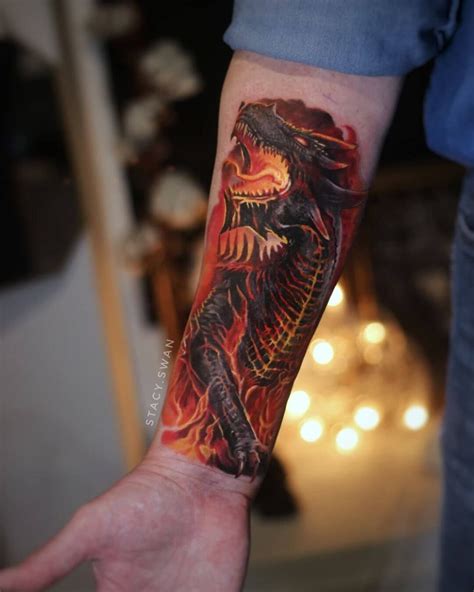 a person with a tattoo on their arm holding up a red and black fire breathing dragon