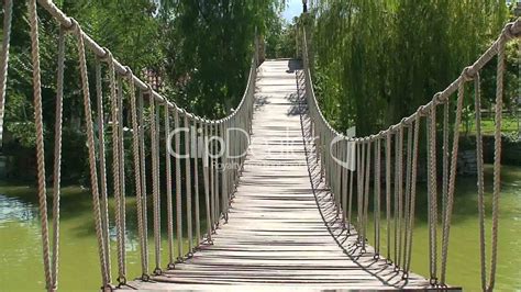 Old Wooden Rope Bridge across a Slimy Pond