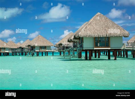 Huts at Bora Bora over turquoise waters and blue sky Stock Photo - Alamy