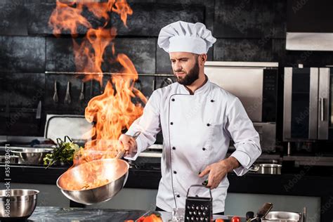 Chef cook food with fire at kitchen restaurant. Cook with wok at kitchen. Stock Photo | Adobe Stock