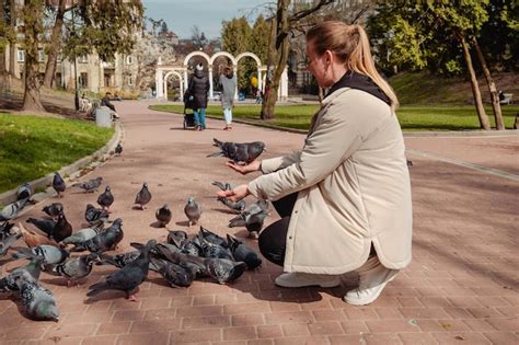 Premium Photo | Woman feeding pigeons in the park