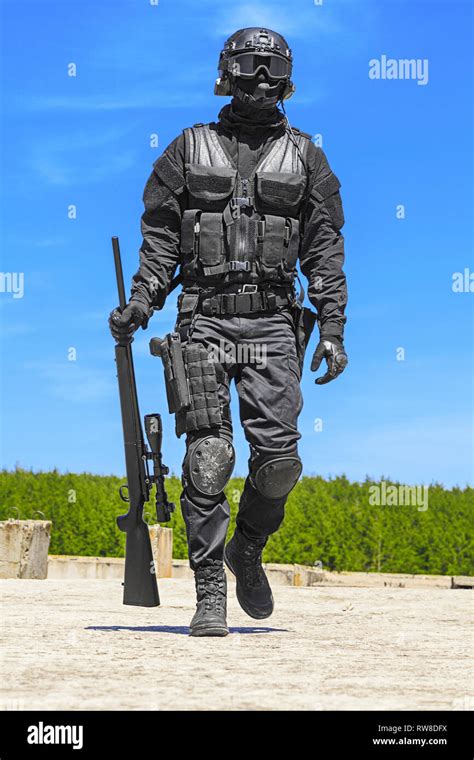 SWAT police operator with sniper rifle in black uniform, walking towards camera Stock Photo - Alamy