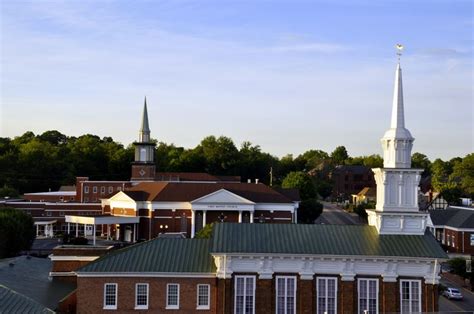 an aerial view of a church with steeple in the background