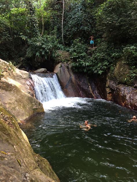 two people swimming in the water near a waterfall