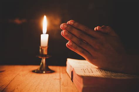 Free Photo | Men praying on the bible in the light candles selective focus.