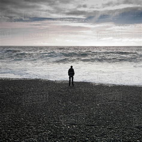 Man standing on black beach looking out to sea, djupalonssandur, snaefellsnes, iceland - Stock ...