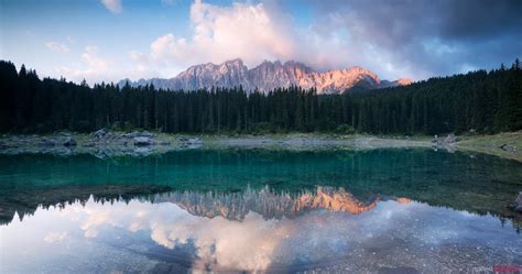 - Lake Carezza at sunrise with mountain range reflected Dolomites Italy ...