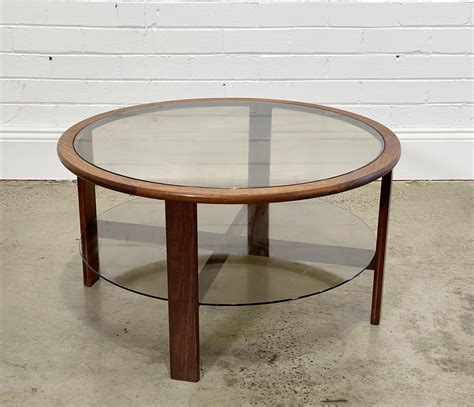 Lot - Vintage round teak coffee table with smoky glass top & shelf below (h43 x d80cm)