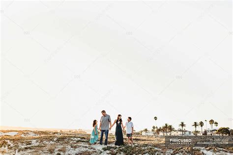 Happy family holding hands standing on beach — caucasian, sleeves - Stock Photo | #423934324