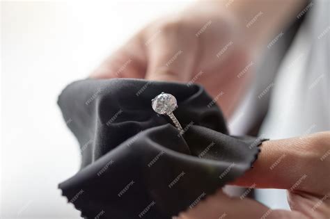 Premium Photo | Jeweller cleaning jewelry diamond ring with fabric cloth