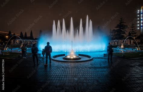 Ice blue water fountain at night with family and random people ...