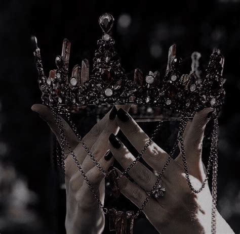 a black and white photo of a woman wearing a crown with chains around her hands