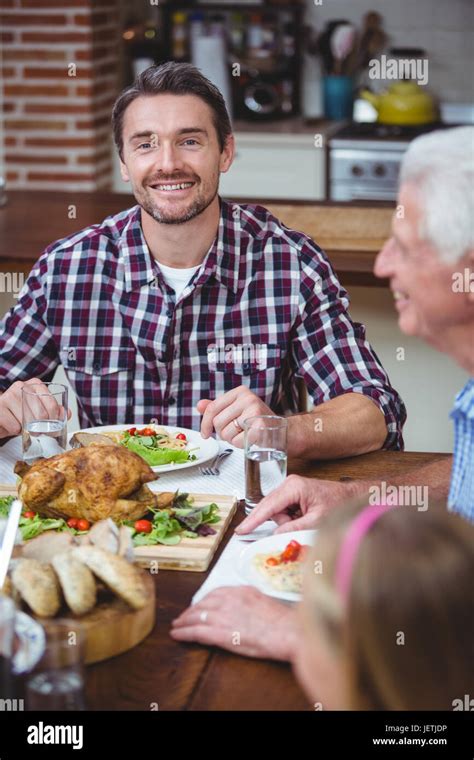 Smiling father sitting at dining table Stock Photo - Alamy