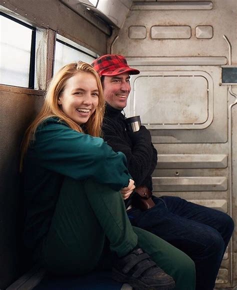 a man and woman sitting on a subway car smiling at the camera, with their arms around each other