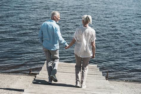 casual elderly couple holding hands and walking on riverside at daytime - Stock Photo - Dissolve