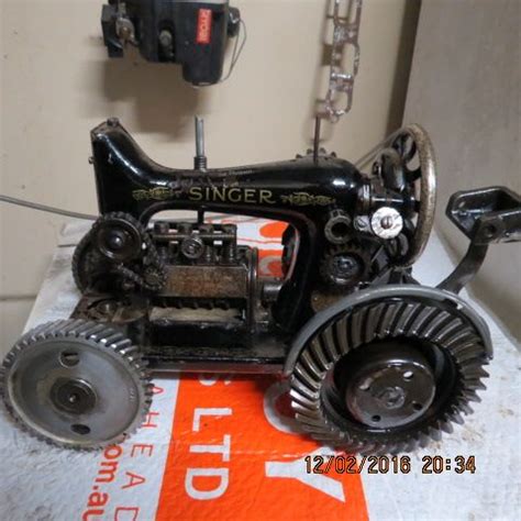 an old black sewing machine sitting on top of a white cloth covered table next to a wall