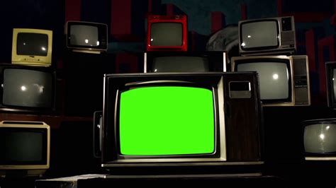 an old television with a green screen surrounded by other tvs in the dark room