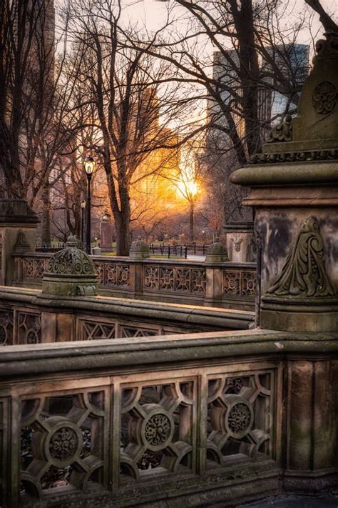 the sun is setting over an old bridge