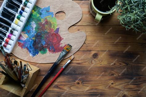 Premium Photo | Paint brushes watercolors and palette on wooden table creative workspace