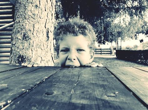 Premium Photo | Portrait of boy biting wooden table outdoors