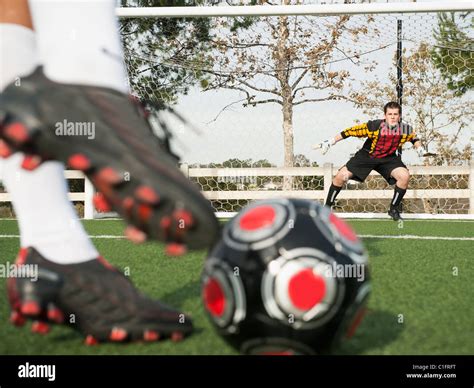 Soccer player kicking ball into goal on soccer field Stock Photo - Alamy