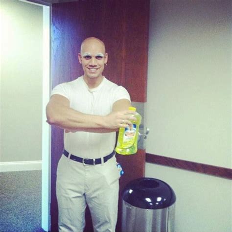 a man in white shirt and khaki pants holding up a bottle of liquid