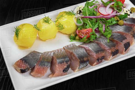 Sliced salted herring with vegetables on white plate - Stock Photo - Dissolve