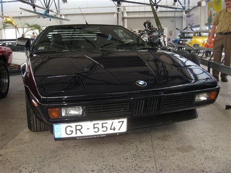 a black car parked in a garage next to other cars and people standing around it