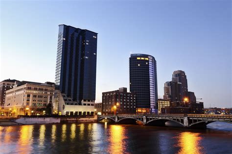 The Grand Rapids, Michigan skyline still sparkles with night lights, as the morning sun begins ...