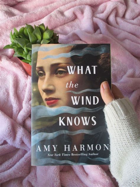 the book what the wind knows is held up by someone's hand on a pink blanket