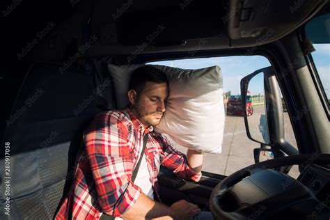 Truck driver sleeping in cabin of his truck due to driving long distances and overworking ...