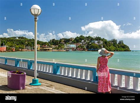 Woman on malecon (seaside promenade) and hillside houses, Naguabo ...