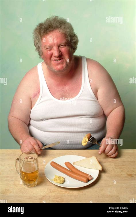 Fat man in undershirt eating two sausages with mustard Stock Photo ...