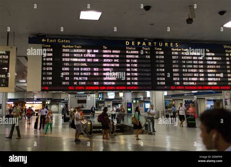 Travelers watch the train departure board at Penn Station in New Stock ...