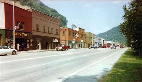 an old photo of a small town with cars parked on the side of the road