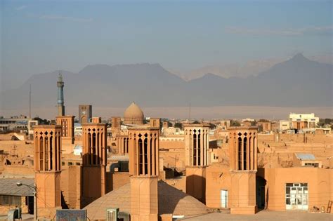 a city with tall buildings and mountains in the backgrouds, including two minarets