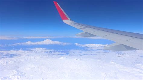 The picturesque view from airplane window over the wing on snowy ...