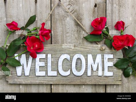 Weathered wood welcome sign hanging on wooden door with flower border ...