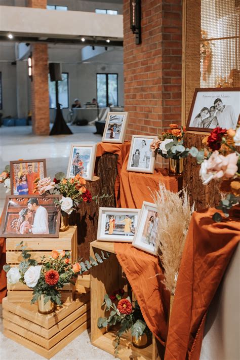 A mini photo display at the wedding reception clad in a burnt orange theme, decorated with ...