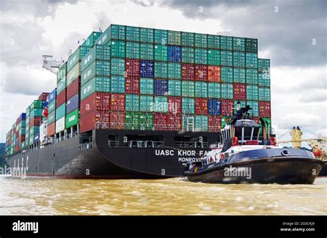 Huge panamax container cargo ship in the panama canal aided by a tug boat Stock Photo - Alamy