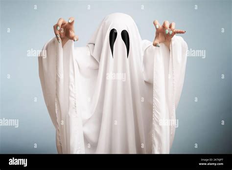 Halloween Concept. A white ghost with black eyes, made from a bedsheet on blue background Stock ...